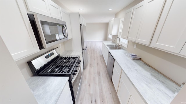 kitchen with sink, stainless steel appliances, light hardwood / wood-style flooring, and white cabinets