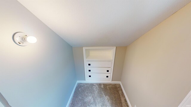 hallway featuring carpet floors, a textured ceiling, and built in features