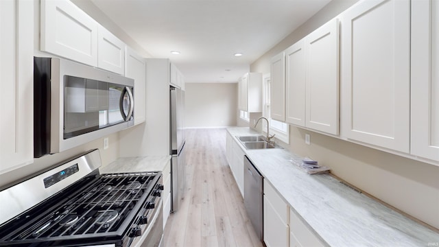 kitchen featuring sink, appliances with stainless steel finishes, white cabinetry, and light hardwood / wood-style floors