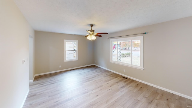 unfurnished room with a textured ceiling, light wood-type flooring, and ceiling fan