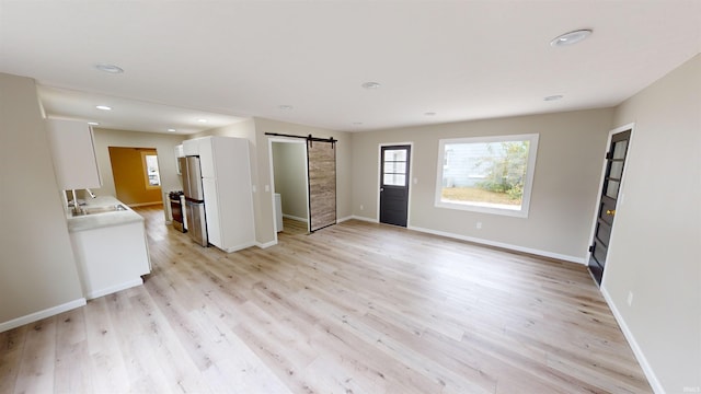 interior space with light hardwood / wood-style flooring, a barn door, and sink