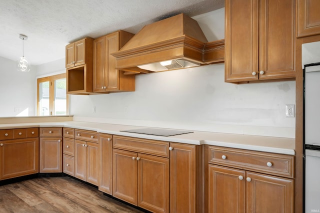 kitchen featuring a textured ceiling, black electric cooktop, pendant lighting, custom exhaust hood, and dark wood-type flooring