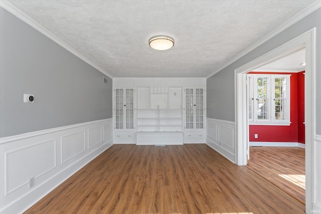 interior space featuring hardwood / wood-style flooring, ornamental molding, and a textured ceiling