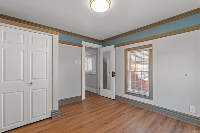 unfurnished bedroom with a closet, ornamental molding, and hardwood / wood-style flooring