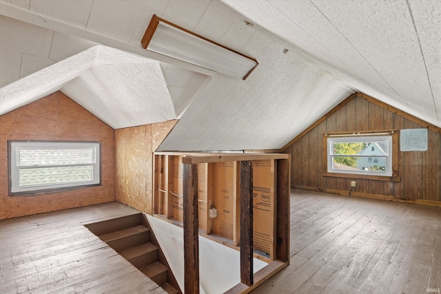 bonus room with lofted ceiling, wooden walls, and light hardwood / wood-style flooring