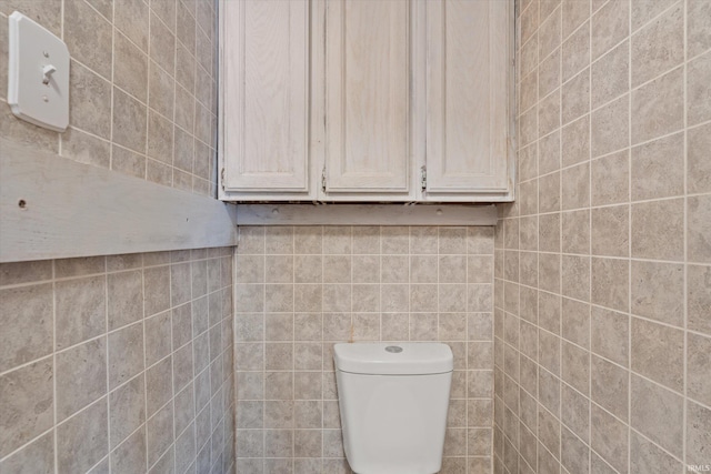 bathroom with toilet and tile walls