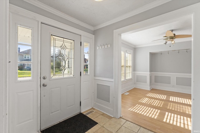 foyer with ornamental molding, light hardwood / wood-style flooring, and ceiling fan