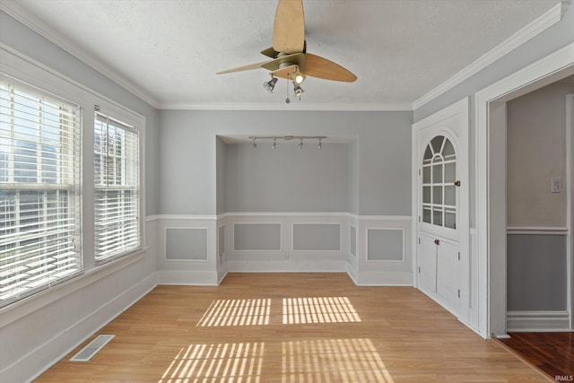 interior space featuring track lighting, ceiling fan, a textured ceiling, light hardwood / wood-style flooring, and ornamental molding