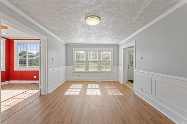 unfurnished room featuring light hardwood / wood-style flooring, ornamental molding, and a textured ceiling