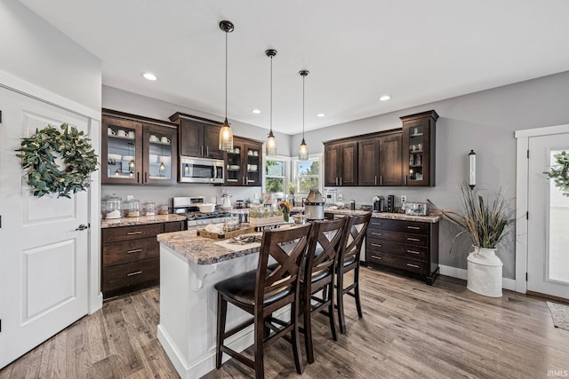 kitchen featuring appliances with stainless steel finishes, dark brown cabinetry, a center island, and a breakfast bar area