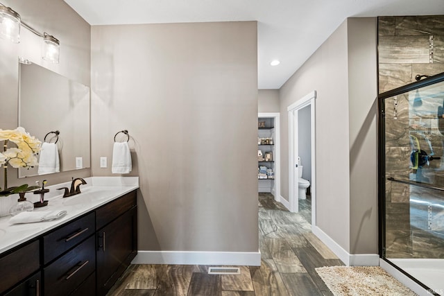 bathroom with toilet, an enclosed shower, hardwood / wood-style floors, and vanity