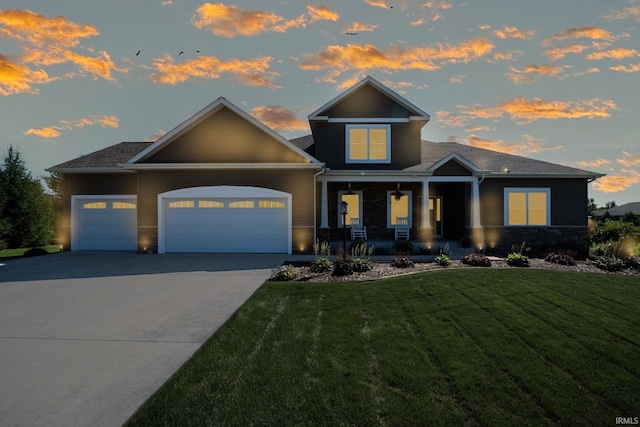 view of front facade with a porch, a yard, and a garage