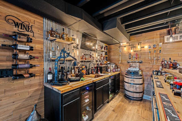 wine cellar with light hardwood / wood-style flooring, wet bar, beverage cooler, and wood walls