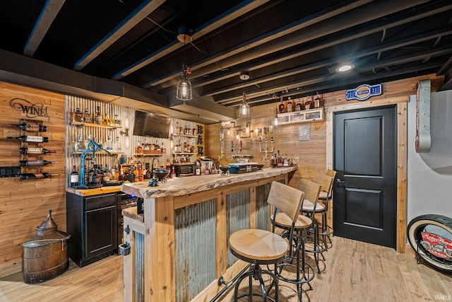 bar with wooden walls, light hardwood / wood-style flooring, pendant lighting, and wood counters