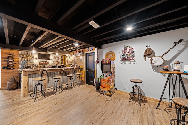 bar featuring light hardwood / wood-style flooring, wood walls, and beamed ceiling