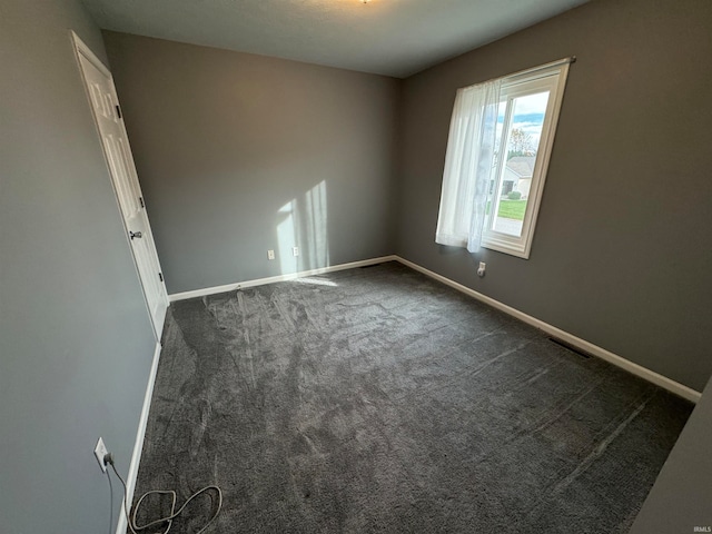 spare room featuring dark colored carpet