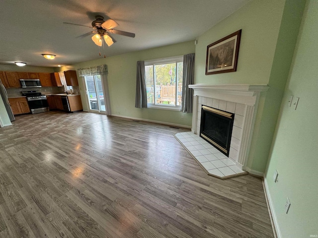 unfurnished living room featuring ceiling fan, light wood-type flooring, and a fireplace