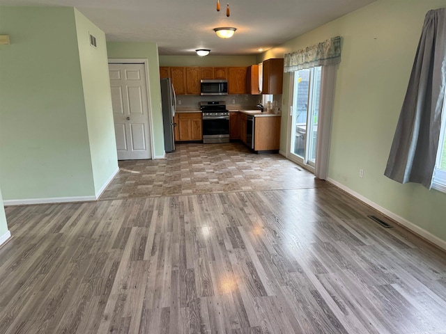 kitchen featuring sink, light hardwood / wood-style floors, stainless steel appliances, and a healthy amount of sunlight