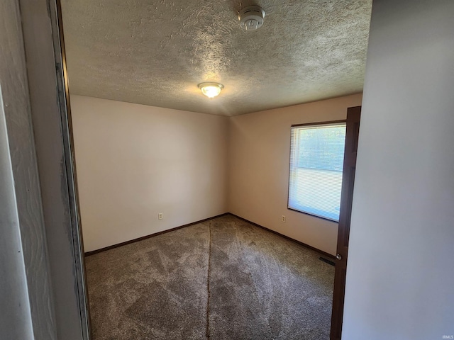 carpeted empty room featuring a textured ceiling