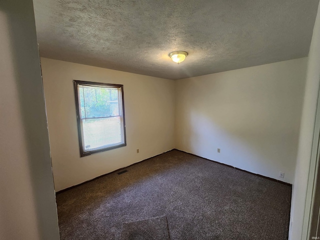 carpeted empty room featuring a textured ceiling