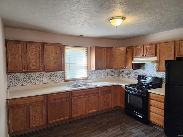 kitchen featuring dark wood-type flooring, black appliances, sink, and a textured ceiling