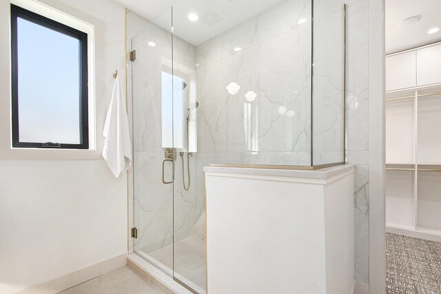full bathroom featuring a marble finish shower, a walk in closet, recessed lighting, and tile patterned flooring