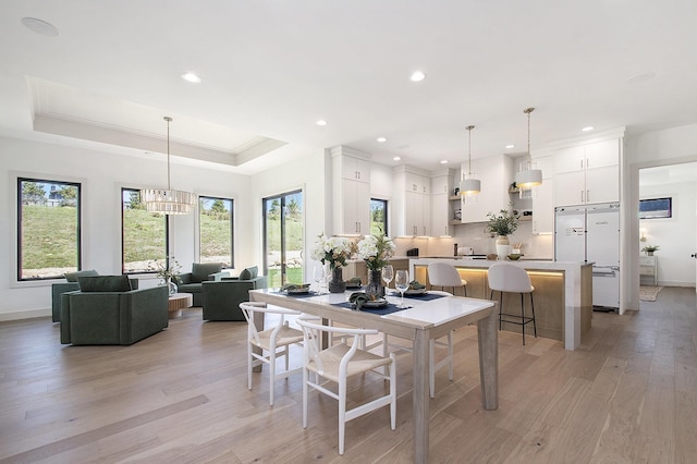 dining room with light wood-style floors, recessed lighting, a tray ceiling, a chandelier, and baseboards