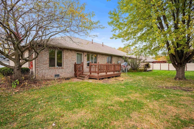 rear view of house featuring a wooden deck and a lawn