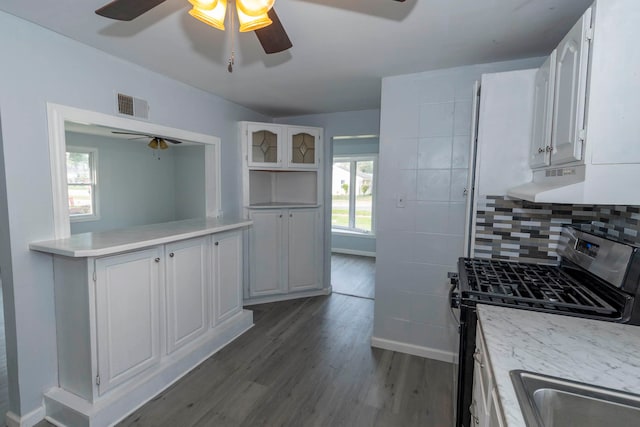 kitchen with dark wood-type flooring, gas range, plenty of natural light, and white cabinets