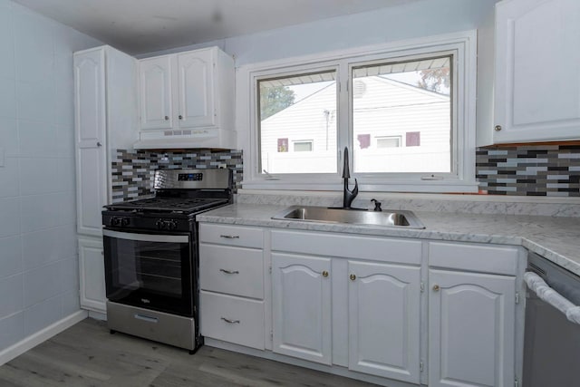 kitchen with sink, appliances with stainless steel finishes, white cabinetry, and light hardwood / wood-style floors