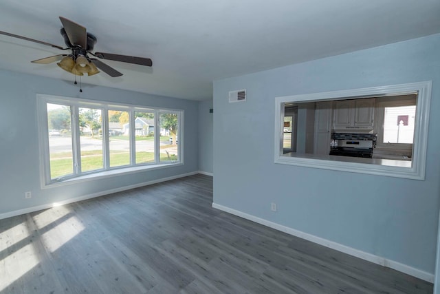 empty room with a wealth of natural light, hardwood / wood-style floors, and ceiling fan