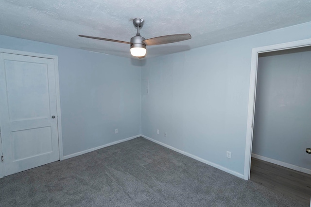 spare room featuring dark colored carpet, a textured ceiling, and ceiling fan