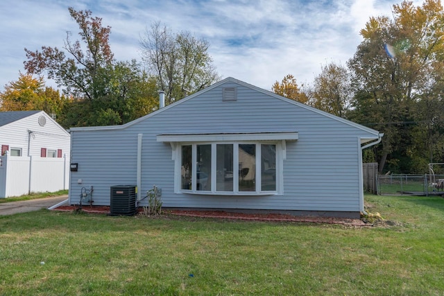 rear view of property with a yard and central AC unit