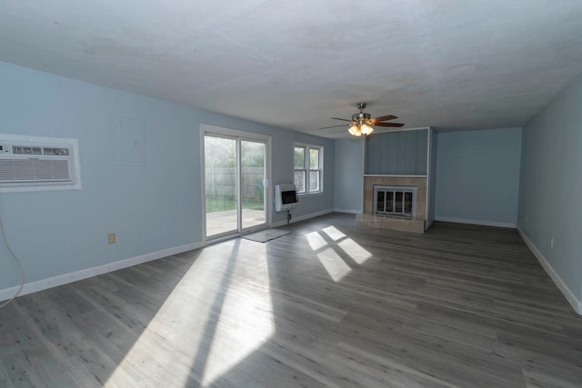 unfurnished living room featuring a fireplace, wood-type flooring, heating unit, and ceiling fan