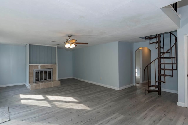 unfurnished living room featuring hardwood / wood-style floors, a tile fireplace, and ceiling fan