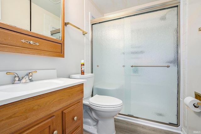 bathroom featuring vanity, a shower with shower door, wood-type flooring, and toilet