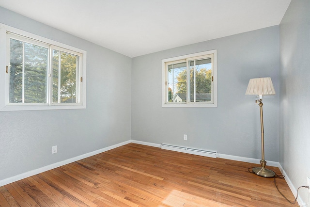 empty room with hardwood / wood-style flooring and a baseboard heating unit