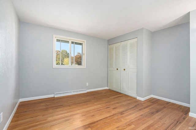 unfurnished bedroom with a baseboard radiator, a closet, and light hardwood / wood-style floors