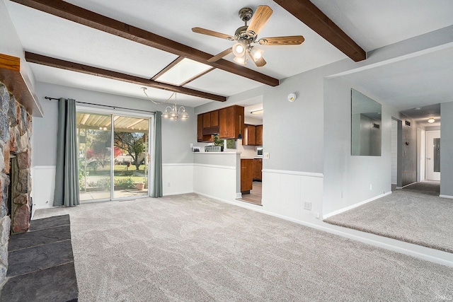 unfurnished living room featuring beamed ceiling, ceiling fan with notable chandelier, and carpet