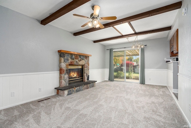 unfurnished living room featuring light carpet, a stone fireplace, beamed ceiling, and ceiling fan