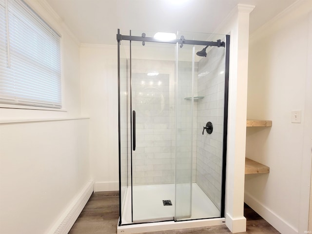 bathroom featuring crown molding, wood-type flooring, a baseboard radiator, and an enclosed shower