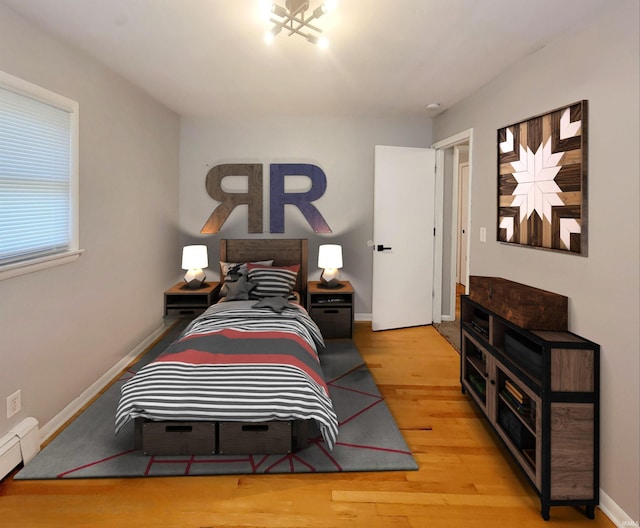 bedroom with wood-type flooring and baseboard heating