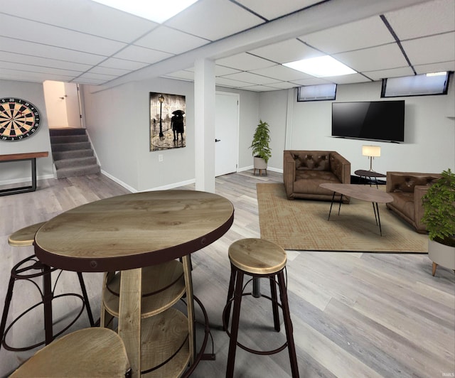 bar with light hardwood / wood-style flooring and a paneled ceiling