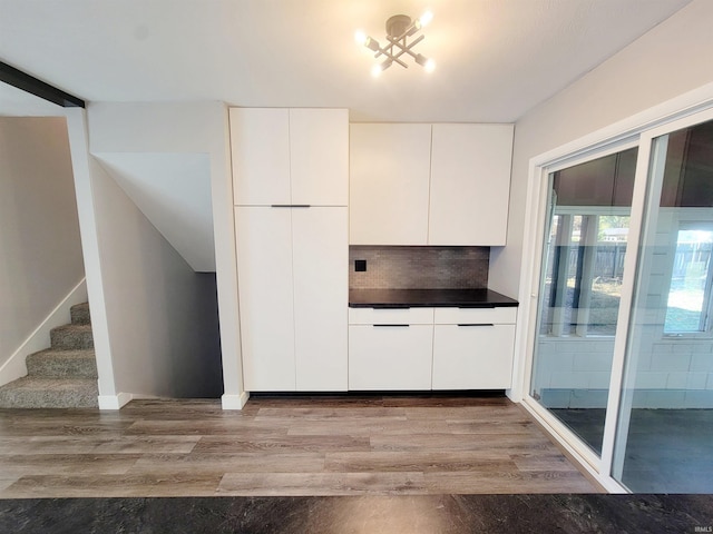 kitchen featuring an inviting chandelier, hardwood / wood-style floors, white cabinets, and tasteful backsplash