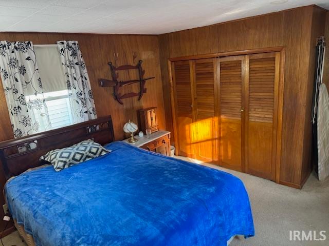 carpeted bedroom featuring a closet and wood walls