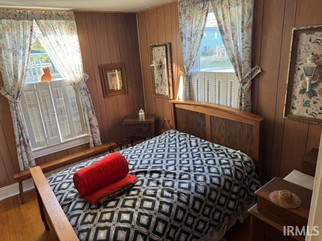 bedroom featuring hardwood / wood-style floors and wooden walls