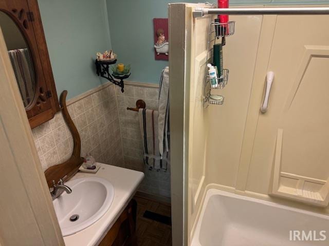 bathroom with vanity, tile walls, and shower with separate bathtub