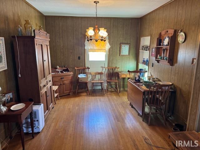 dining area with an inviting chandelier, light hardwood / wood-style floors, and wood walls