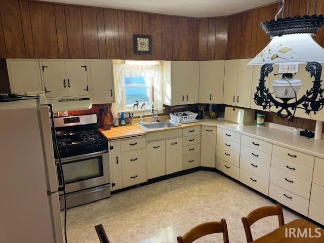 kitchen featuring stainless steel stove, sink, and white refrigerator