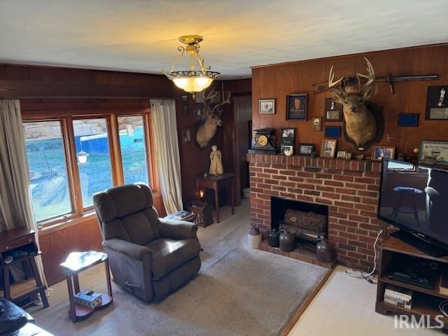 living room with wooden walls, carpet flooring, and a brick fireplace